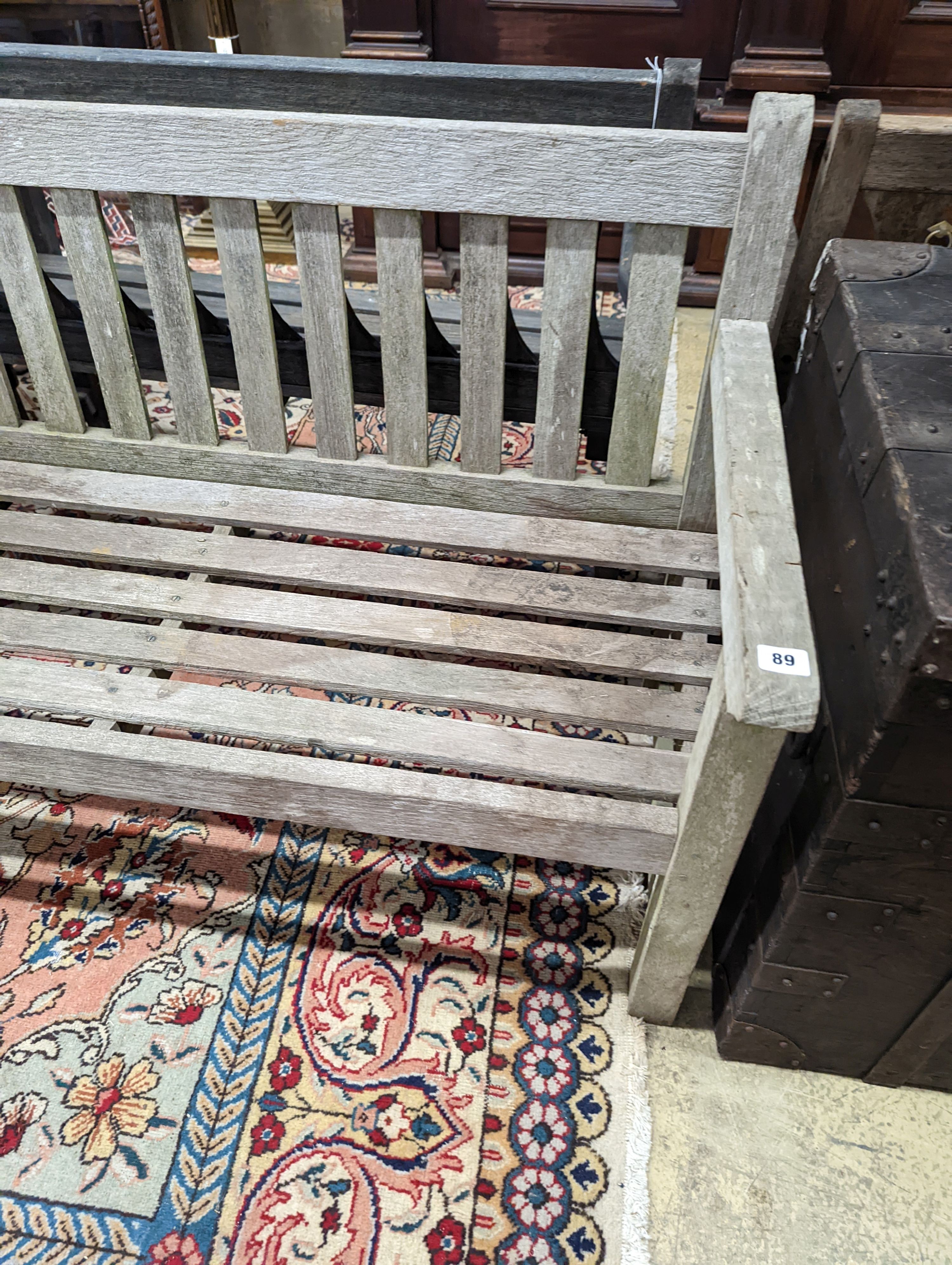 A weathered teak slatted garden bench